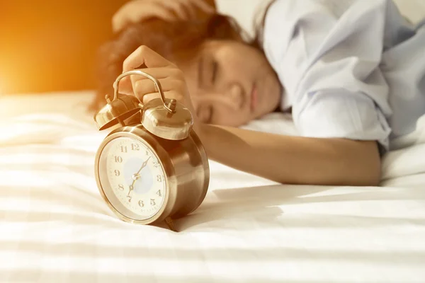 Jeune femme asiatique au lit essayant de se réveiller avec réveil — Photo