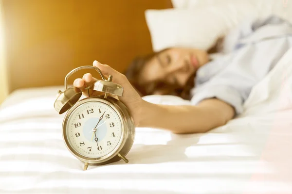 Wanita Asia muda di tempat tidur mencoba untuk bangun dengan jam alarm — Stok Foto