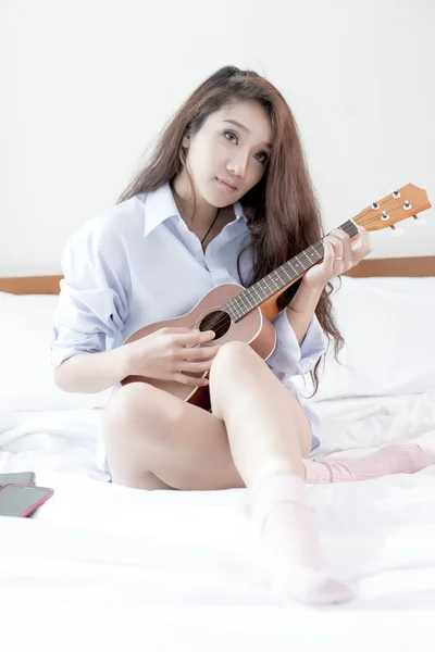 Jonge dame speelt Ukulele in haar slaapkamer — Stockfoto