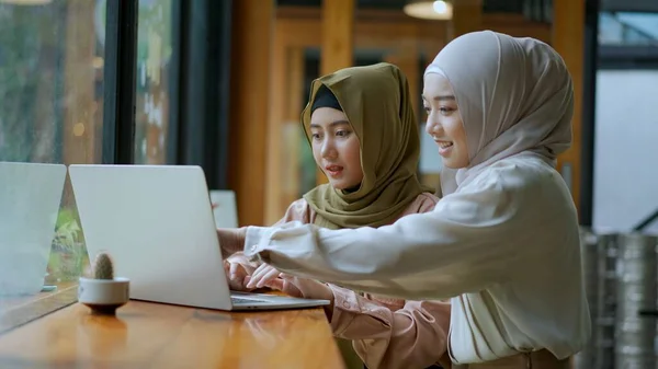 Selective focus, Two beautiful Muslim women are working on laptop computer and discussing in a coffee shop, muslim business working concept