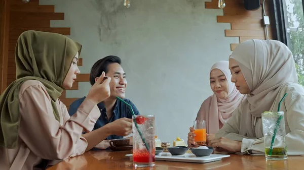 年轻的穆斯林男子和三个穿着头巾的漂亮女子在咖啡店里度过了一段悠闲的时光 他们喜欢一起吃糕点 蛋糕和软饮料 — 图库照片