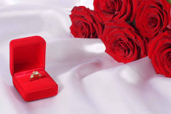 Golden diamond ring in box and red rose