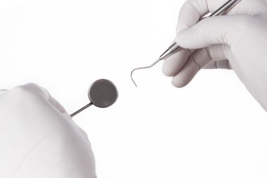 Hasta muayene sırasında aletlerini tutarak diş hekimi 