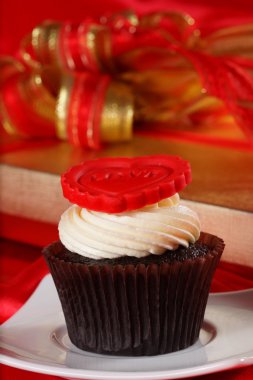 Cupcake üstte ve hediyeler kırmızı saten kutularındaki kırmızı bir kalp ile 