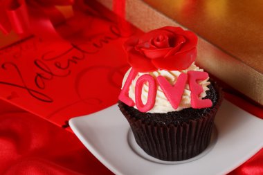 Cupcake üstte ve hediyeler kırmızı saten b kutularındaki kırmızı bir gül ile