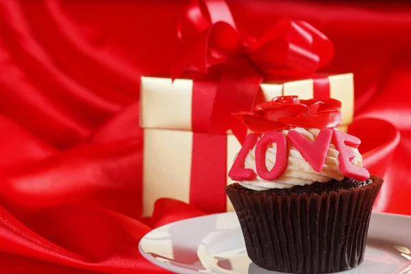 Cupcake com uma rosa vermelha no topo e presentes em caixas de cetim vermelho b — Fotografia de Stock