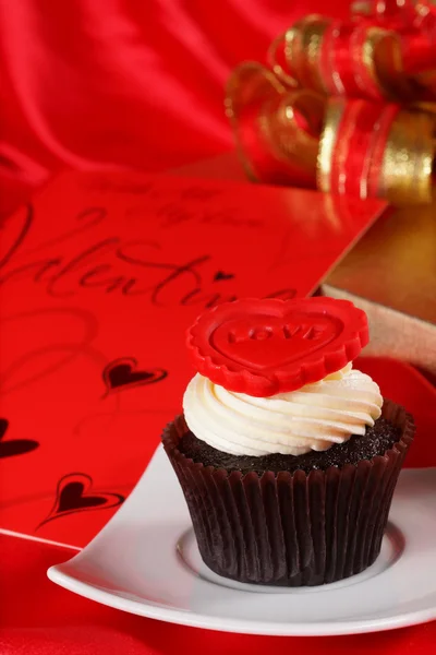 Cupcake met een rood hart op boven- en geschenken in vakken op rood satijn — Stockfoto