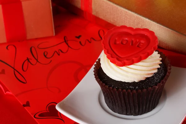 Cupcake met een rood hart op boven- en geschenken in vakken op rood satijn — Stockfoto