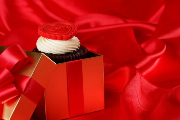 Cupcake met een rood hart op de top in giften vakken op rode satijnen rug — Stockfoto