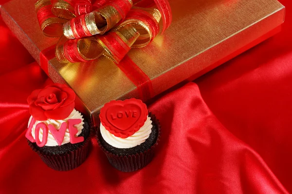 Luxury cupcake with gifts boxes on red satin background — Stock Photo, Image