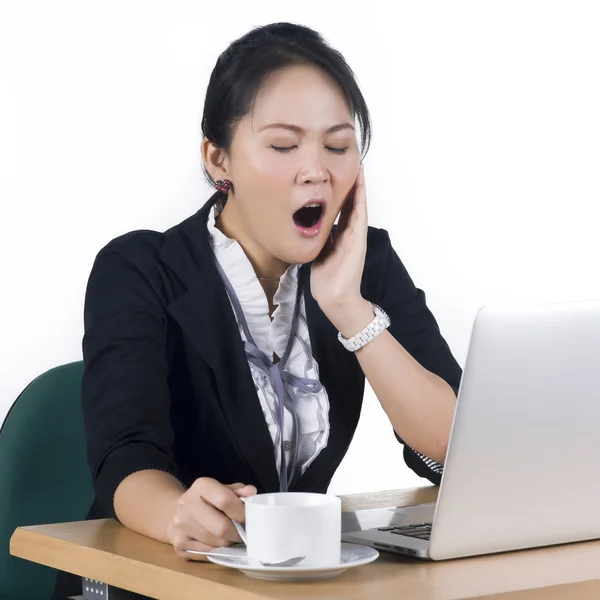 Jonge zakenvrouw geeuwen op haar bureau met een kopje koffie — Stockfoto