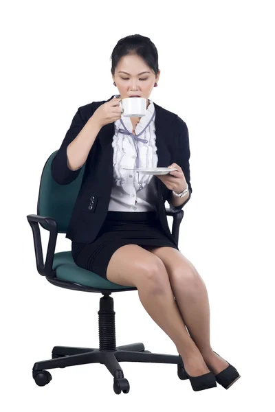 Mulher de negócios sentada na cadeira do escritório com uma xícara de café — Fotografia de Stock