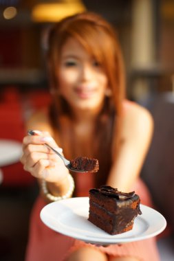 Çikolatalı kek yeme kafede oturan genç güzel kadın. Fo