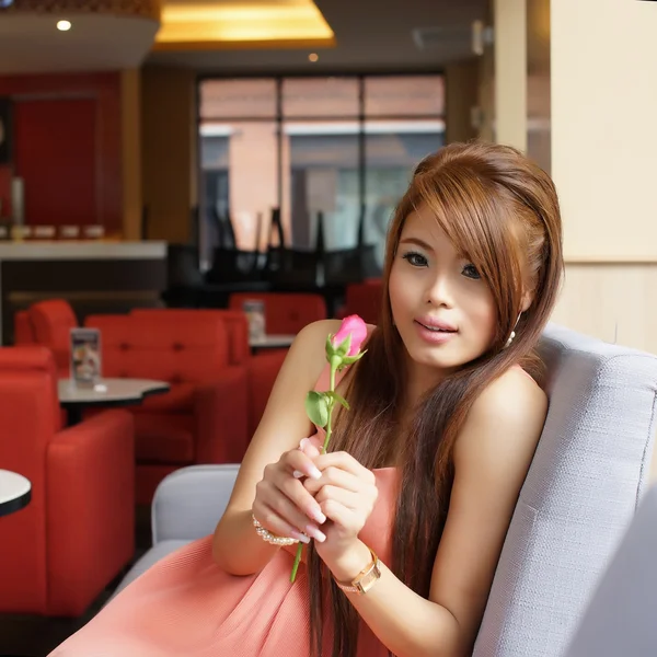 Kırmızı bir gül café'de tutan genç güzel kadın portresi — Stok fotoğraf