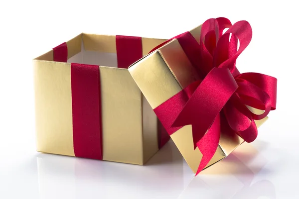 Beautiful gold present box with red bow and ribbons — Stock Photo, Image