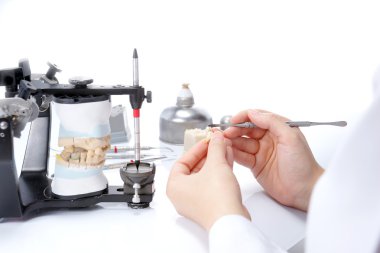 Diş teknisyeni, diş laboratuarında eklem makinesi ile çalışıyor.