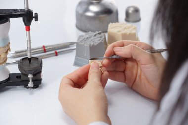 Diş teknisyeni, diş laboratuarında eklem makinesi ile çalışıyor.