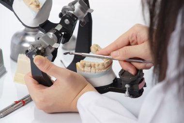 Diş teknisyeni, diş laboratuarında eklem makinesi ile çalışıyor.