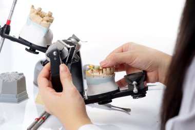 Diş teknisyeni, diş laboratuarında eklem makinesi ile çalışıyor.