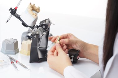 Diş teknisyeni, diş laboratuarında eklem makinesi ile çalışıyor.