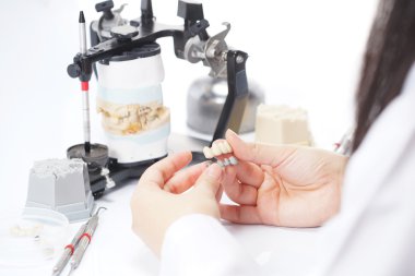 Diş teknisyeni, diş laboratuarında eklem makinesi ile çalışıyor.