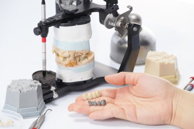 Diş teknisyeni, diş laboratuarında eklem makinesi ile çalışıyor.