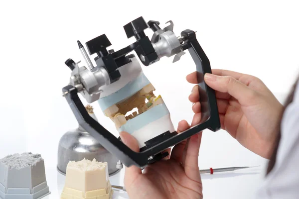 Diş teknisyeni, diş laboratuarında eklem makinesi ile çalışıyor.