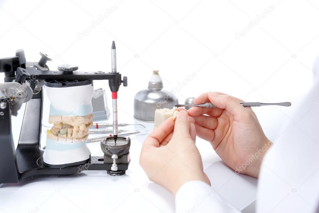 Dental technician working with articulator in dental laboratory