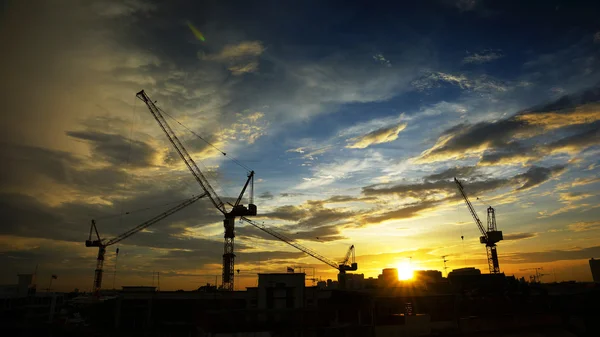 Paesaggio industriale con sagome di gru sul tramonto ba — Foto Stock