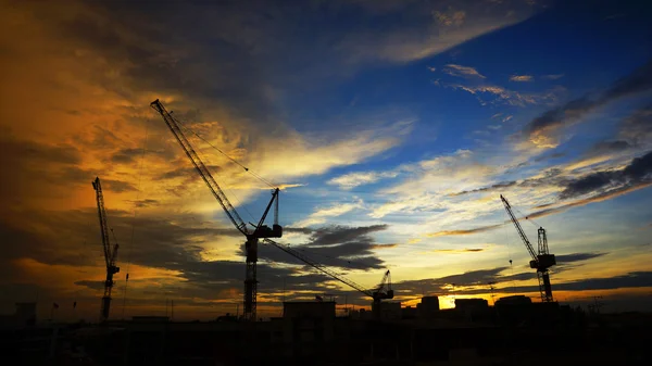 Paesaggio industriale con sagome di gru sul tramonto ba — Foto Stock