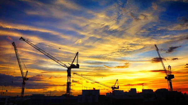 Paesaggio industriale con sagome di gru sul tramonto ba — Foto Stock