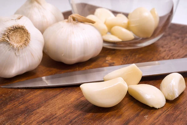 Weiße Knoblauchzwiebeln und Knoblauchzehen, geschält auf einem Holzschneidebrett — Stockfoto