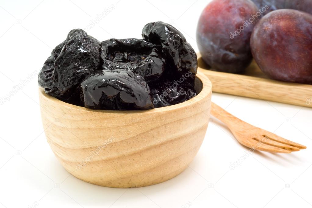 Delicious prunes in wooden bowl and fresh plums
