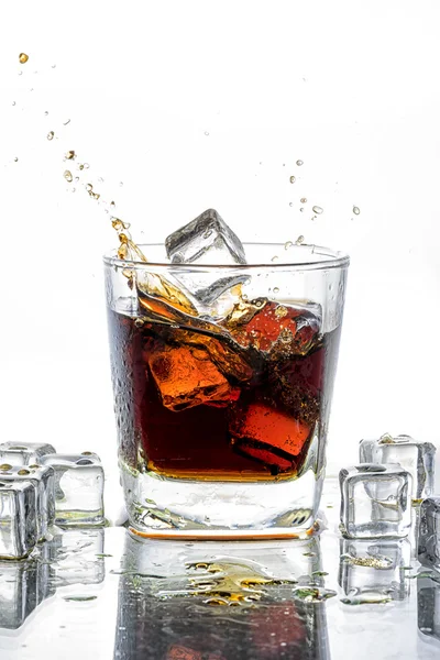 Ice cube wegviel in cola glas en cola spatten — Stockfoto