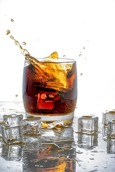 Лёд в стакане колы и брызги колы
