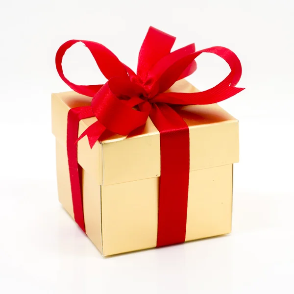 Beautiful gold present box with red bow and ribbons — Stock Photo, Image