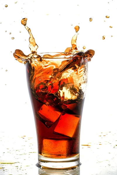 Cubo di ghiaccio caduto nel bicchiere di cola e spruzzi di cola — Foto Stock