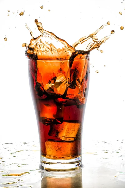 Ice cube droped in cola glass and cola splashing — Stock Photo, Image