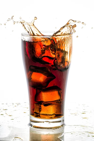 Cubo di ghiaccio caduto nel bicchiere di cola e spruzzi di cola — Foto Stock