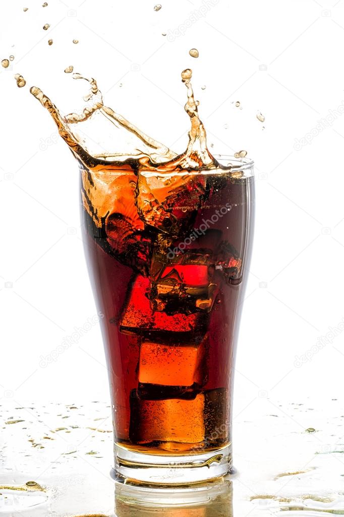Ice cube droped in cola glass and cola splashing