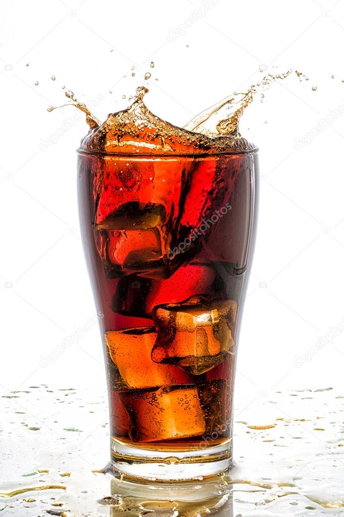 Ice cube droped in cola glass and cola splashing