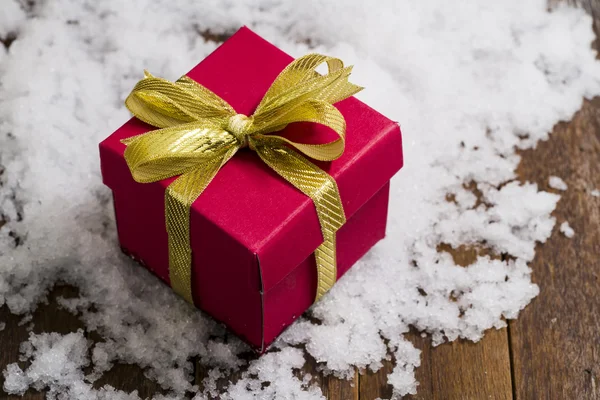 Noel hediye kutusu ile kar üzerinde bir altın şerit yay