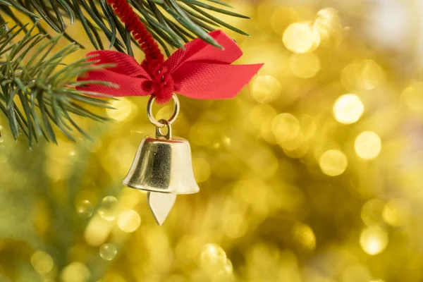 Weihnachtsglockenschmuck hängt mit gelbem Bokeh am Ast — Stockfoto