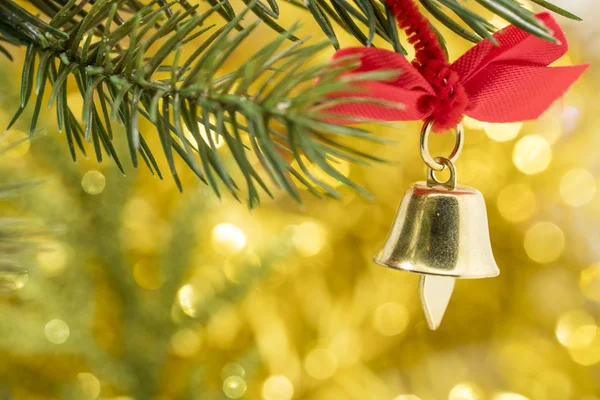 Weihnachtsglockenschmuck hängt mit gelbem Bokeh am Ast — Stockfoto