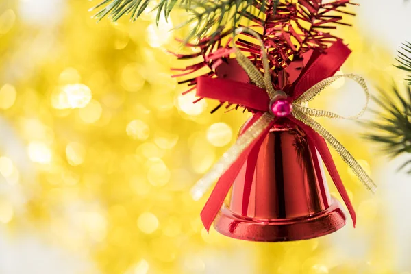 Adorno de campana de Navidad cuelga en rama de árbol con bokeh ba amarillo — Foto de Stock
