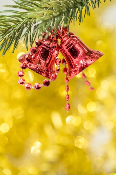 Weihnachtsglockenschmuck hängt mit gelbem Bokeh am Ast — Stockfoto