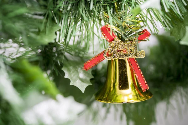 Weihnachtsglockenschmuck hängt an Ast mit grünem Hintergrund — Stockfoto