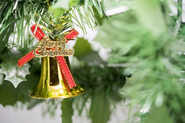 Weihnachtsglockenschmuck hängt an Ast mit grünem Hintergrund — Stockfoto