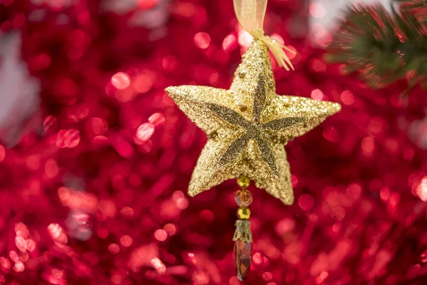 Weihnachtssternschmuck hängt mit rotem Bokeh-Rücken am Ast — Stockfoto