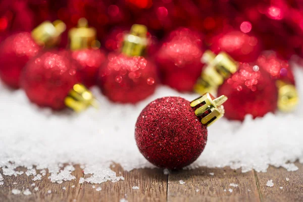 Bolas rojas de Navidad sobre nieve sobre fondo rojo bokeh —  Fotos de Stock